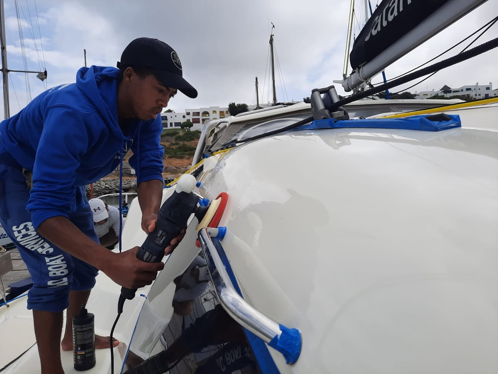 Boat detailing Langebaan team member polishing a boat at a marina